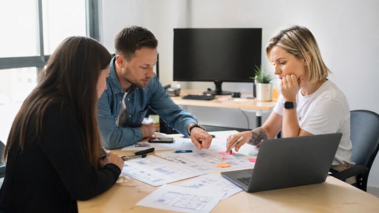 Equipo revisando fases de un proyecto de desarrollo web en una mesa de trabajo